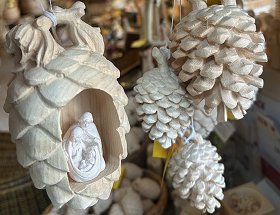 Interessante Details einer weißen Zirbe und vier weißen Latschenkiefern-Zapfen aus Tirol lassen hier bestaunen. In die Zirpe ist ein rechteckiger Hohlraum eingearbeitet, in dem sehr filigran Maria, Joseph und das Christkind zu sehen ist.