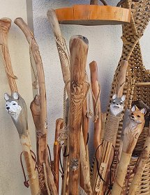 Zahlreiche Wanderstöcke mit Wurzel oder geschnitzten Tieren sind hier in einem Ständer dicht nebeneinander zu sehen. Naturbelassen oder mit farbigen Tierköpfen als Knauf und mit Lederriemen für den besseren Halt sind sie in einer großen Auswahl dargestellt.