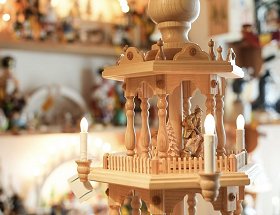 Die Detailansicht im Geschäft zeigt eine Etage einer elektrisch beleuchteten, hölzernen Pyramide mit geschnitzten Figuren.